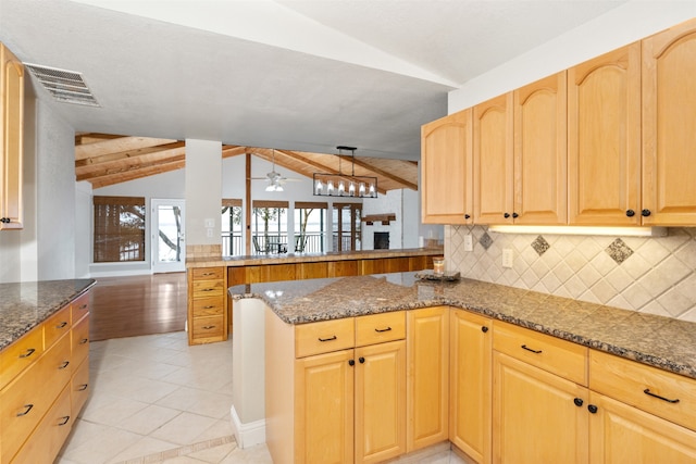 kitchen with backsplash, vaulted ceiling with beams, dark stone counters, light tile patterned floors, and kitchen peninsula