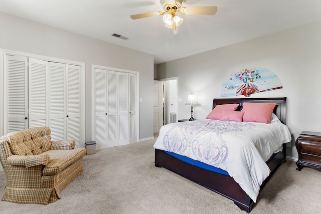 carpeted bedroom with two closets and ceiling fan