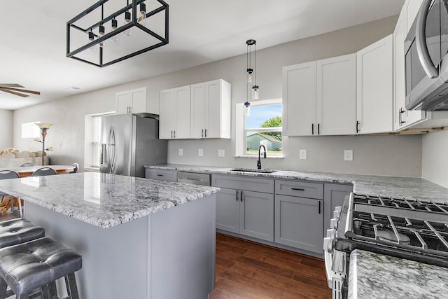 kitchen featuring sink, white cabinetry, stainless steel appliances, a breakfast bar, and dark hardwood / wood-style flooring