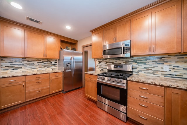 kitchen featuring light stone countertops, stainless steel appliances, wood-type flooring, and decorative backsplash