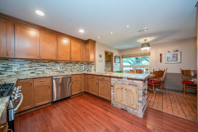 kitchen with appliances with stainless steel finishes, tasteful backsplash, kitchen peninsula, and light stone countertops