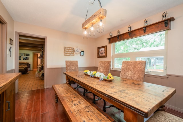 dining area with a wainscoted wall, wood walls, and dark wood-type flooring