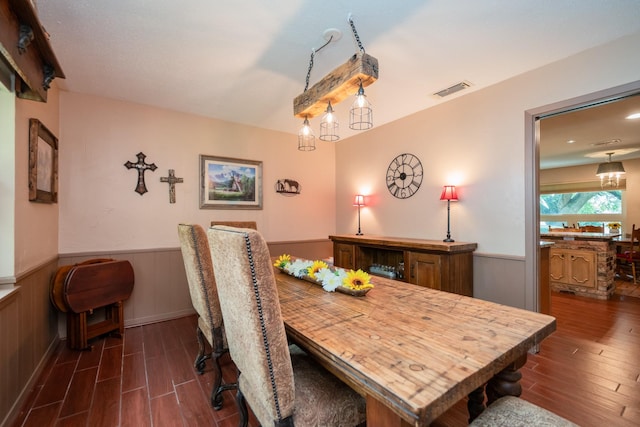 dining space featuring visible vents, wood finished floors, and a wainscoted wall