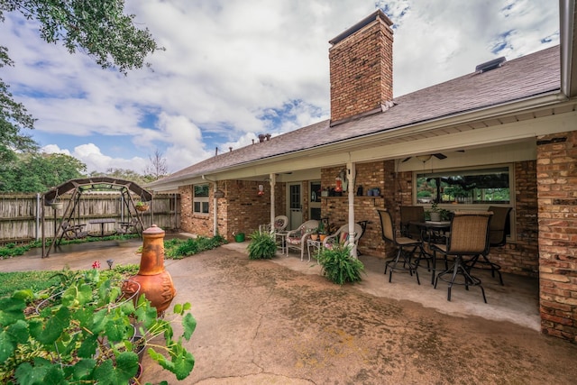 back of property with fence, a chimney, a patio area, and brick siding