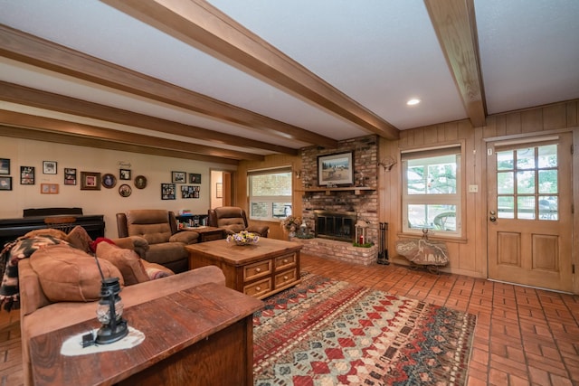 living room with plenty of natural light, brick floor, a fireplace, and beamed ceiling