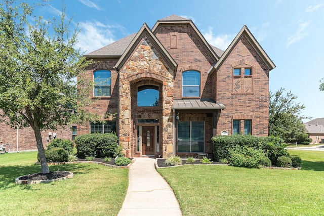 view of front of house with stone siding, brick siding, a front lawn, and a standing seam roof