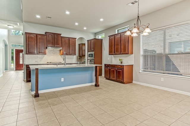 kitchen with visible vents, arched walkways, under cabinet range hood, and stainless steel appliances