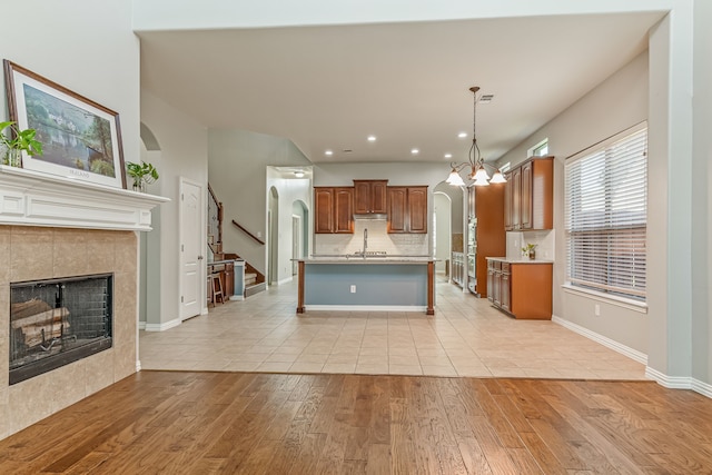 kitchen featuring under cabinet range hood, light countertops, light wood-style flooring, arched walkways, and a sink