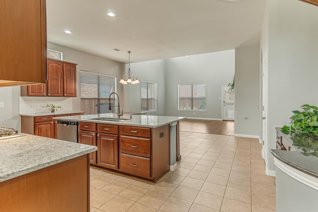 kitchen featuring light tile patterned floors, a sink, decorative backsplash, stainless steel dishwasher, and decorative light fixtures