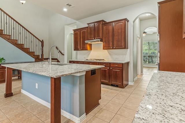 kitchen with arched walkways, visible vents, under cabinet range hood, and a sink