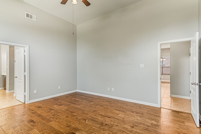 unfurnished bedroom with light wood finished floors, visible vents, high vaulted ceiling, and baseboards