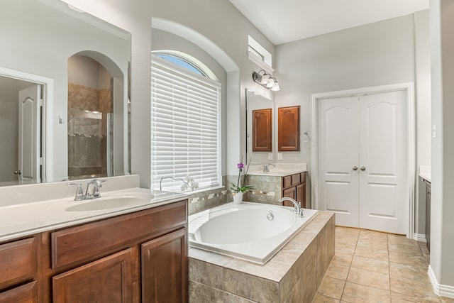 bathroom featuring two vanities, a stall shower, a sink, tile patterned flooring, and a bath