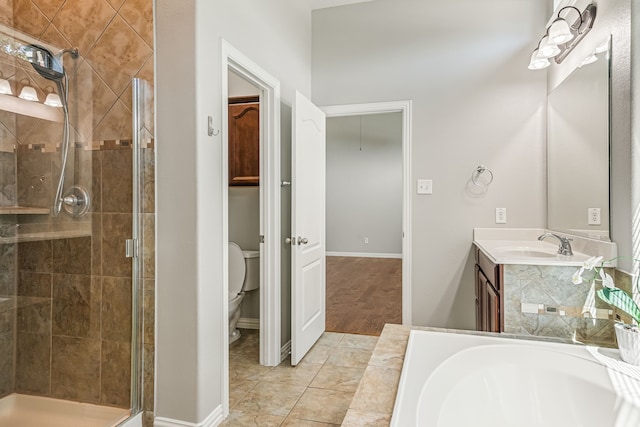 bathroom with vanity, baseboards, a stall shower, a garden tub, and toilet