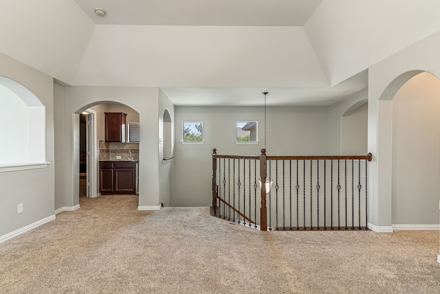 empty room with baseboards, light carpet, and lofted ceiling