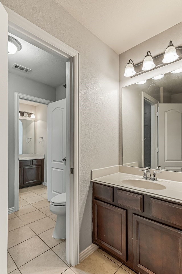 bathroom with visible vents, toilet, vanity, tile patterned floors, and a textured ceiling