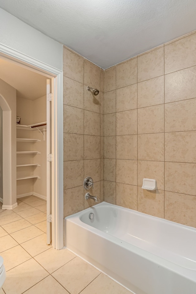 bathroom with a spacious closet, toilet, shower / bathtub combination, tile patterned floors, and a textured ceiling