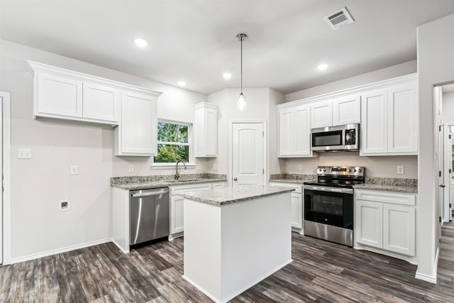 kitchen featuring appliances with stainless steel finishes, sink, a center island, white cabinetry, and hanging light fixtures