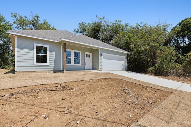 ranch-style home featuring concrete driveway, a shingled roof, and an attached garage