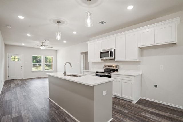 kitchen with an island with sink, hanging light fixtures, stainless steel appliances, white cabinetry, and a sink