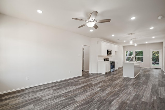 unfurnished living room with baseboards, dark wood-type flooring, and recessed lighting