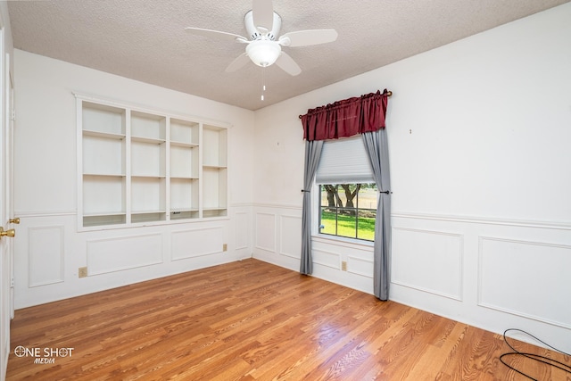 spare room with ceiling fan, light wood-type flooring, and a textured ceiling