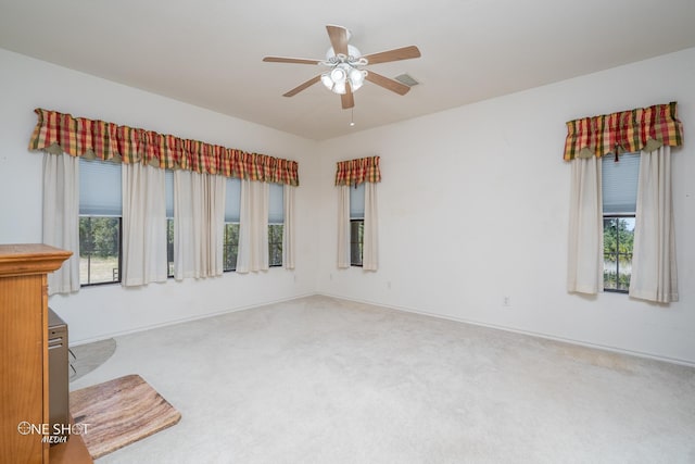 carpeted spare room featuring ceiling fan and a wealth of natural light