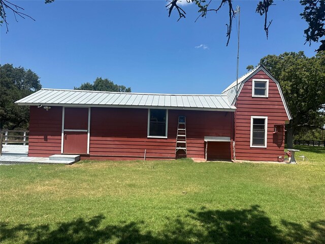 back of property with a yard and an outdoor structure