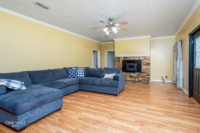 living room featuring ornamental molding, a stone fireplace, and light hardwood / wood-style floors