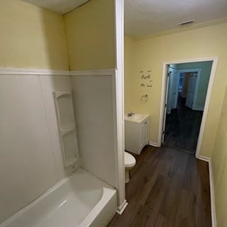 bathroom featuring  shower combination, toilet, and hardwood / wood-style floors