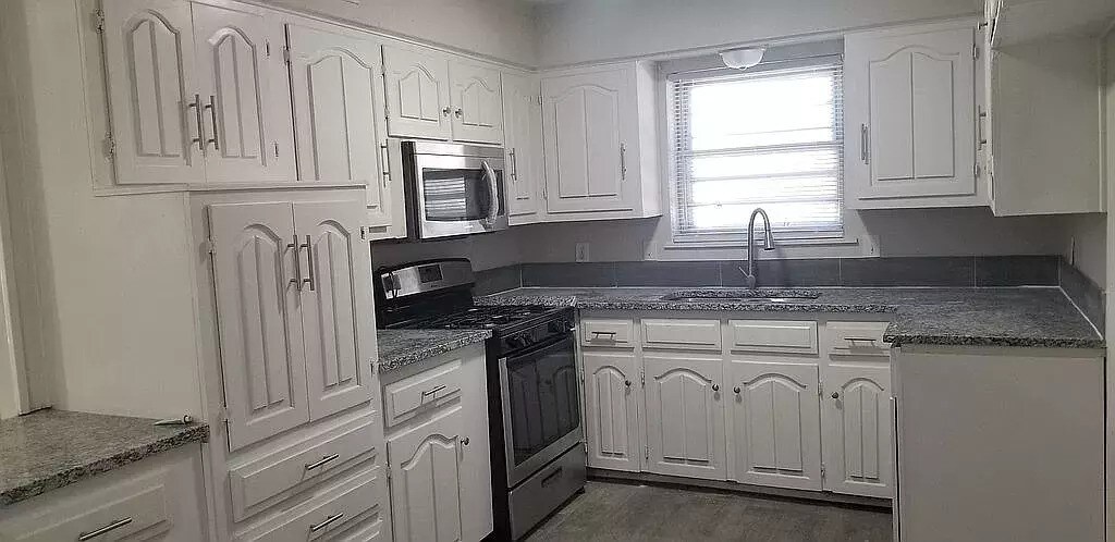 kitchen with appliances with stainless steel finishes, sink, white cabinets, and dark hardwood / wood-style floors