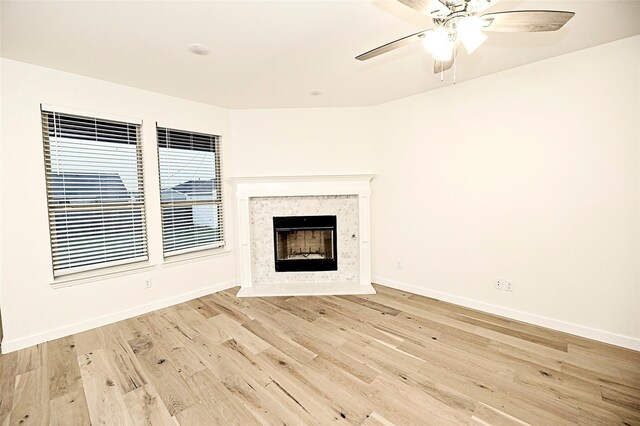 unfurnished living room with a high end fireplace, light hardwood / wood-style flooring, and ceiling fan