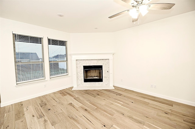 unfurnished living room featuring a high end fireplace, ceiling fan, and light wood-type flooring