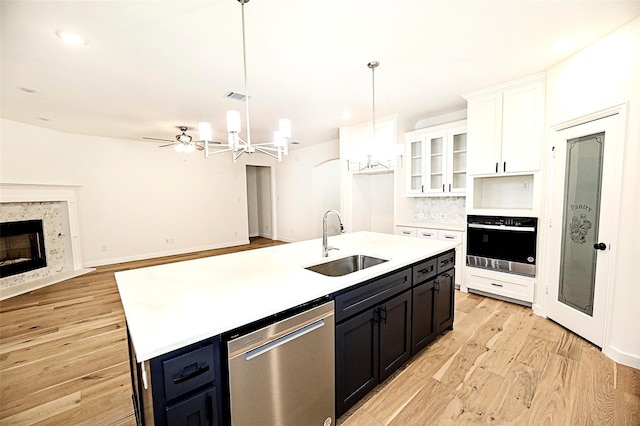 kitchen with decorative light fixtures, white cabinetry, sink, stainless steel appliances, and a center island with sink