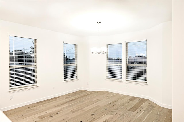 spare room featuring an inviting chandelier and light wood-type flooring