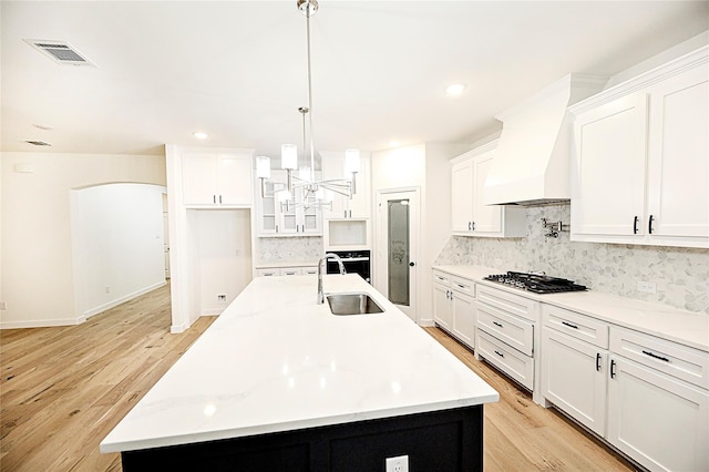 kitchen featuring a center island with sink, white cabinetry, and sink