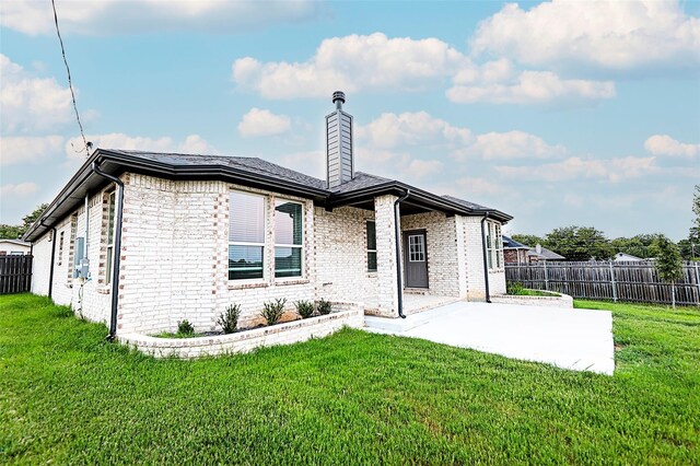 rear view of property featuring a patio and a lawn