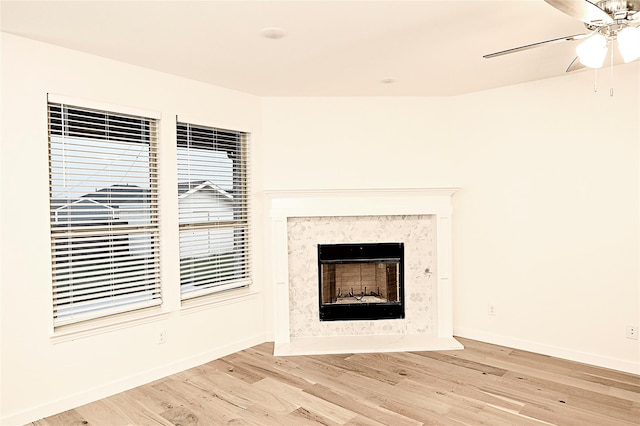 room details with a premium fireplace, ceiling fan, and wood-type flooring