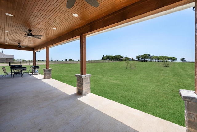 view of patio with a ceiling fan, outdoor dining space, a rural view, and fence