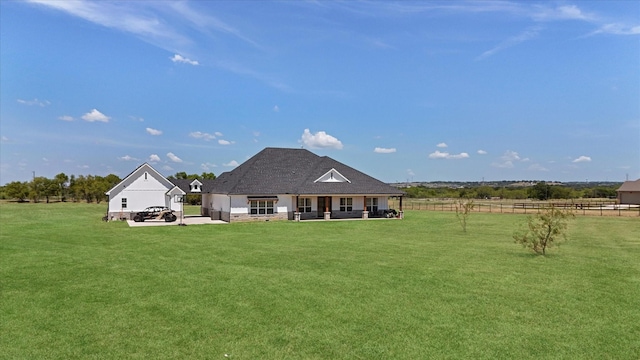 rear view of property featuring a rural view, a lawn, and fence