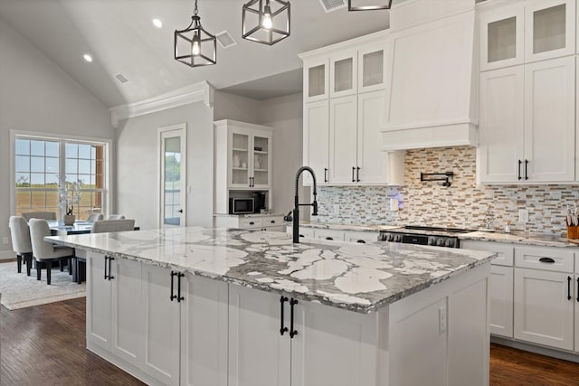 kitchen with a center island with sink, glass insert cabinets, and white cabinets