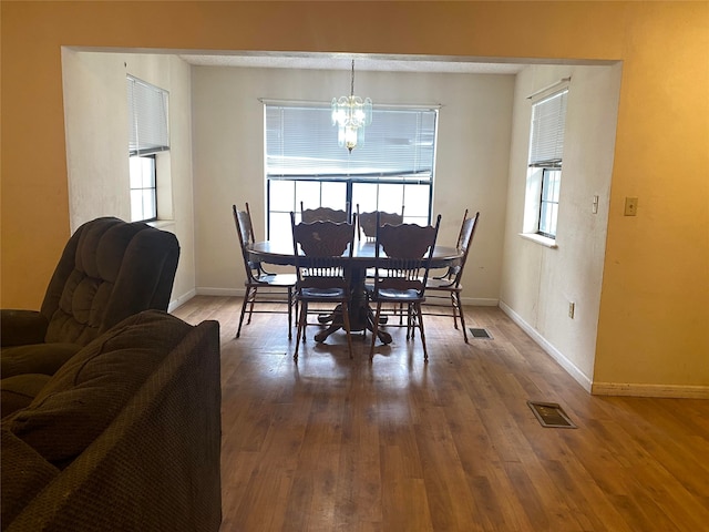 dining room with hardwood / wood-style floors and an inviting chandelier