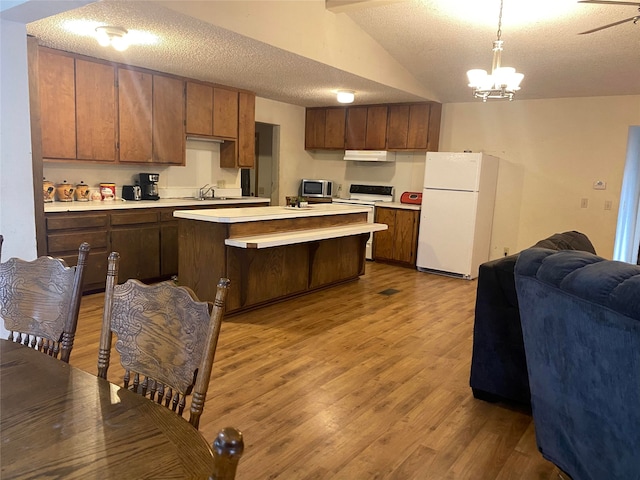 kitchen featuring a textured ceiling, lofted ceiling, an inviting chandelier, white appliances, and wood-type flooring