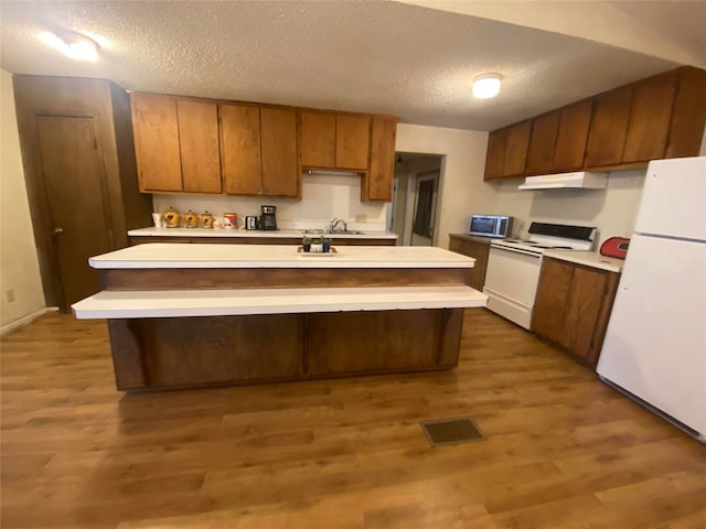 kitchen with a textured ceiling, white appliances, and wood-type flooring