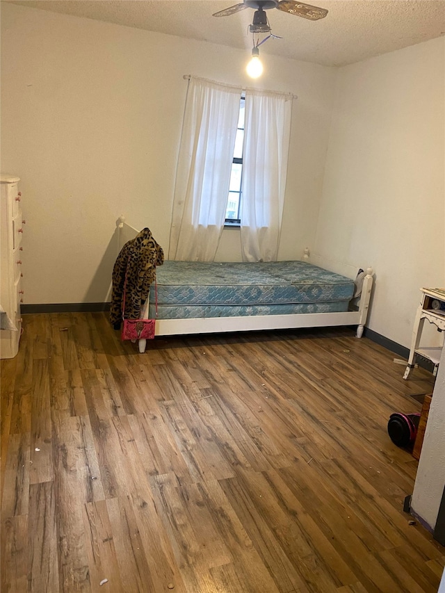 unfurnished bedroom with ceiling fan, a textured ceiling, and hardwood / wood-style floors