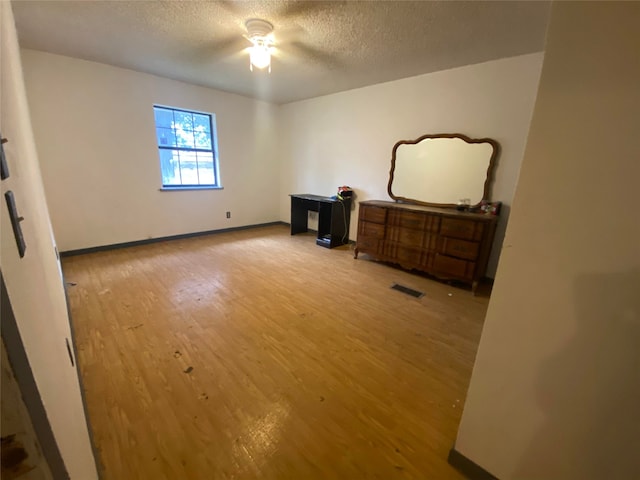 bedroom with ceiling fan, light wood-type flooring, and a textured ceiling