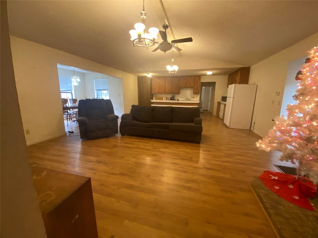 living room with ceiling fan with notable chandelier and light hardwood / wood-style floors