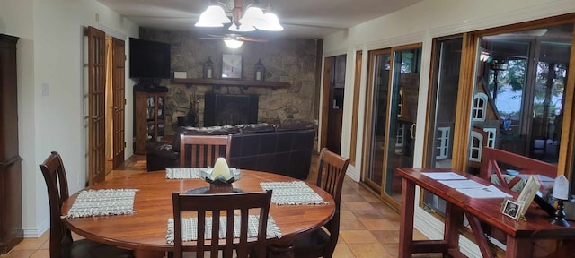 tiled dining area with a stone fireplace and a chandelier