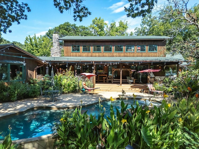 rear view of property with a pool side deck and a patio