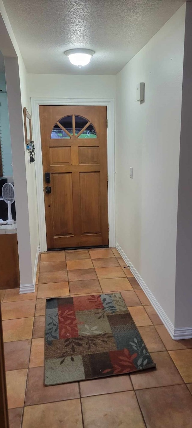 doorway with light tile patterned flooring and a textured ceiling