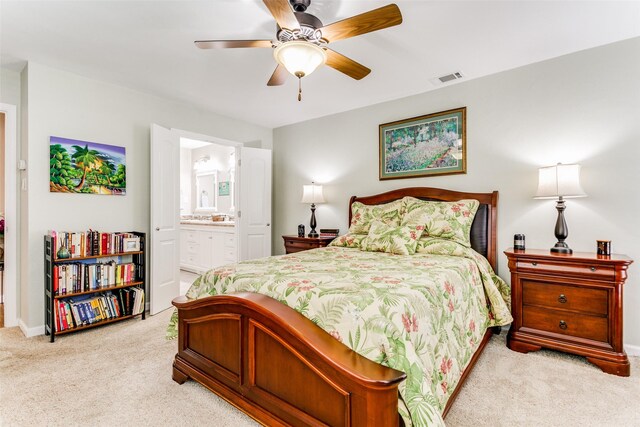 carpeted bedroom with ensuite bathroom and ceiling fan